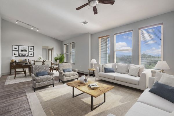 Enclave at the Dominion Bright living room with modern furniture, large windows, a ceiling fan, and a desk in the corner.