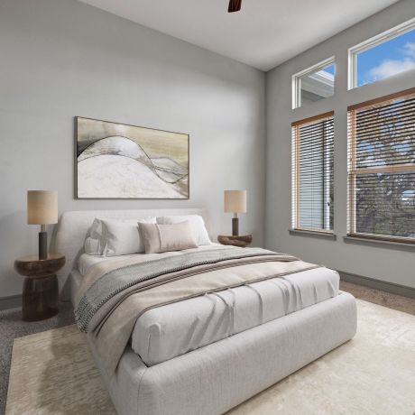 Enclave at the Dominion Modern bedroom with large windows, light-colored bedding, abstract wall art, and two bedside lamps.